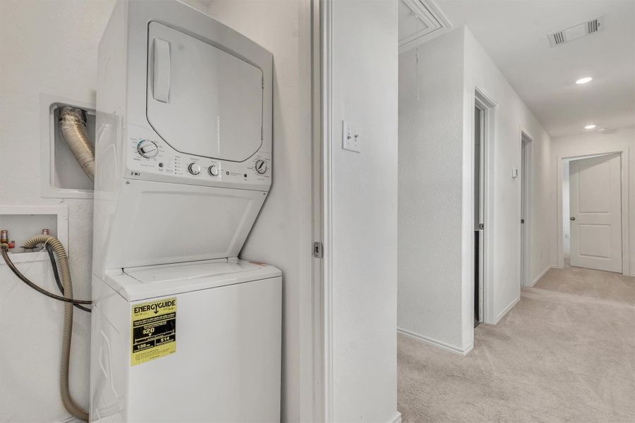 An efficient laundry space seamlessly connects to a carpeted hallway leading to bedrooms. An efficient laundry space seamlessly connects to a carpeted hallway leading to bedrooms.