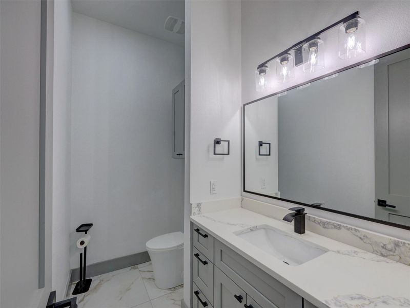 Modern stone counters and classic tile flooring define this stylish bathroom layout.