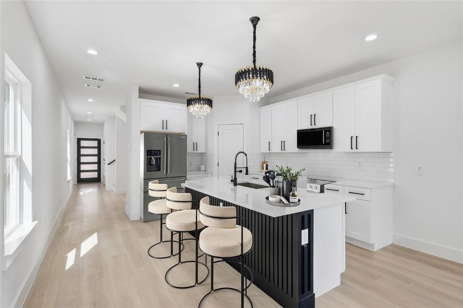 Kitchen with a breakfast bar area, light wood-type flooring, backsplash, and recessed lighting