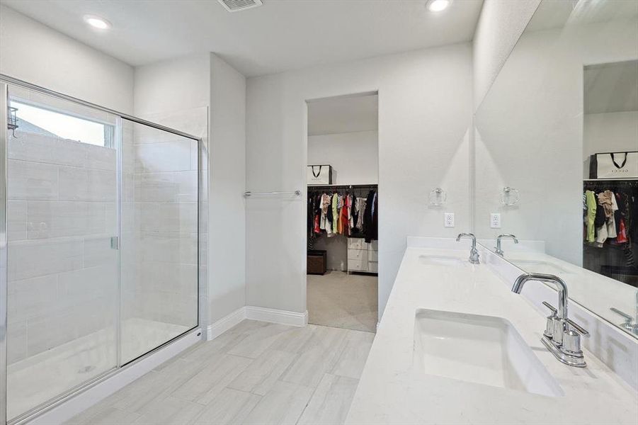 Bathroom featuring a shower with shower door, tile flooring, and dual bowl vanity