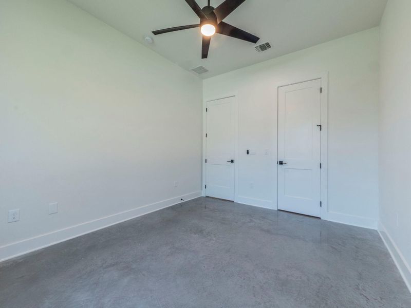 Unfurnished bedroom featuring concrete floors and ceiling fan Unfurnished bedroom featuring concrete floors and ceiling fan