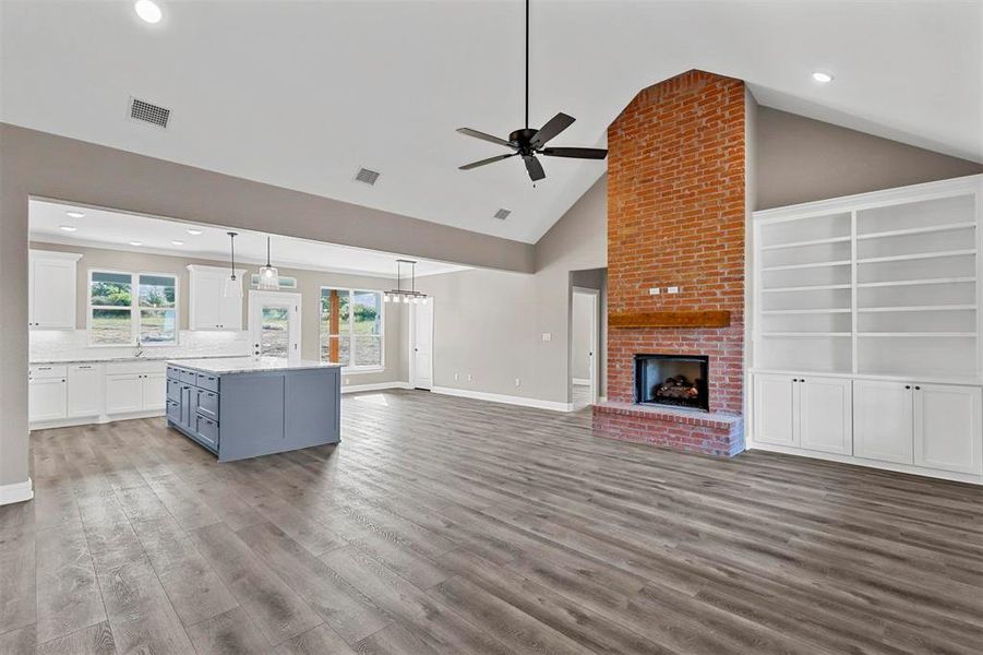 Unfurnished living room featuring a fireplace, sink, high vaulted ceiling, light hardwood / wood-style flooring, and ceiling fan