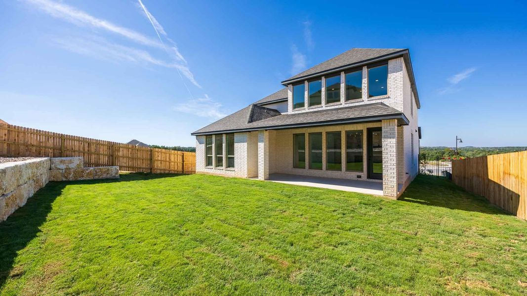 Rear view of house featuring roof with shingles, a fenced backyard, a patio area, and brick siding
