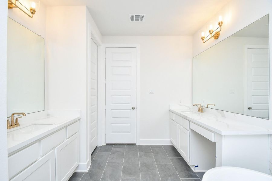 A luxurious bathroom with dual sinks, elegant lighting, and plenty of storage space.