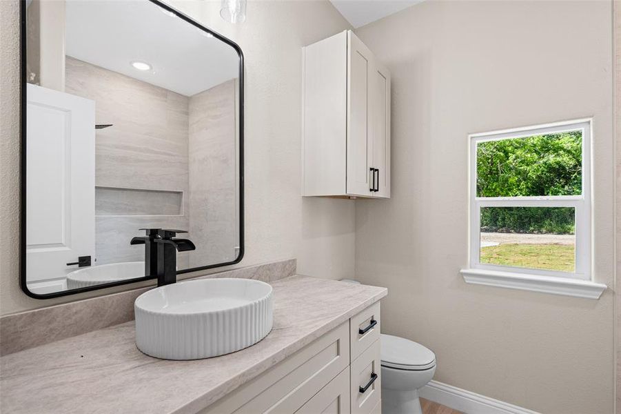 Bathroom featuring a modern vessel sink, matte black faucet, and a large framed mirror