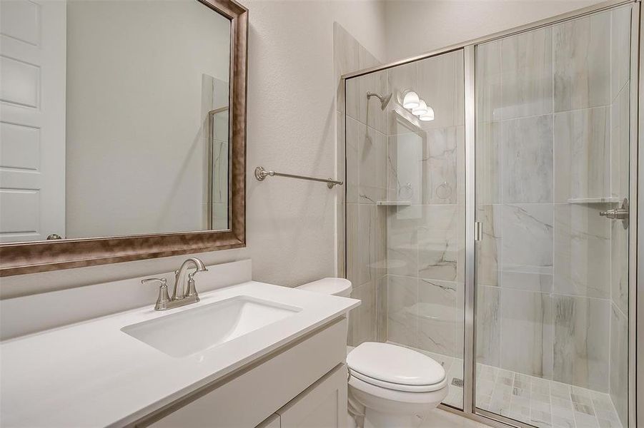 Bathroom featuring toilet, vanity, and a shower with shower door