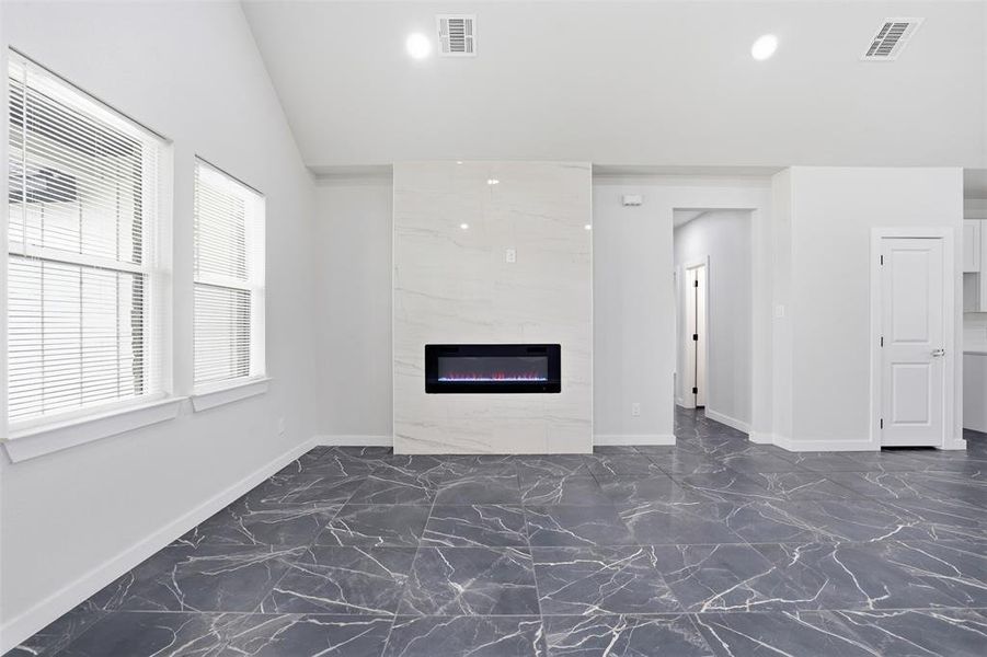 Spacious living area featuring a vaulted ceiling and dark tile flooring with white veining