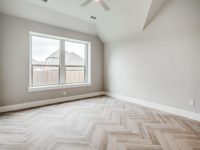 Unfurnished room featuring a ceiling fan, lofted ceiling, baseboards, and visible vents