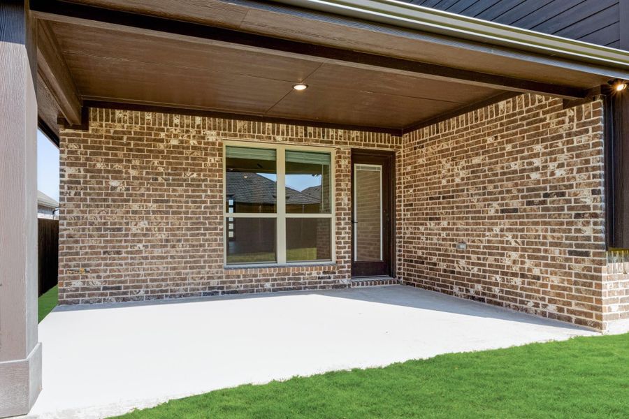 Covered back patio with concrete floor, brick exterior wall, and wood ceiling with recessed lighting
