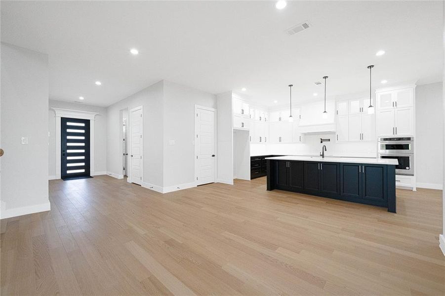Kitchen featuring stainless steel double oven, light countertops, white cabinets, a sink, and recessed lighting Kitchen featuring stainless steel double oven, light countertops, white cabinets, a sink, and recessed lighting