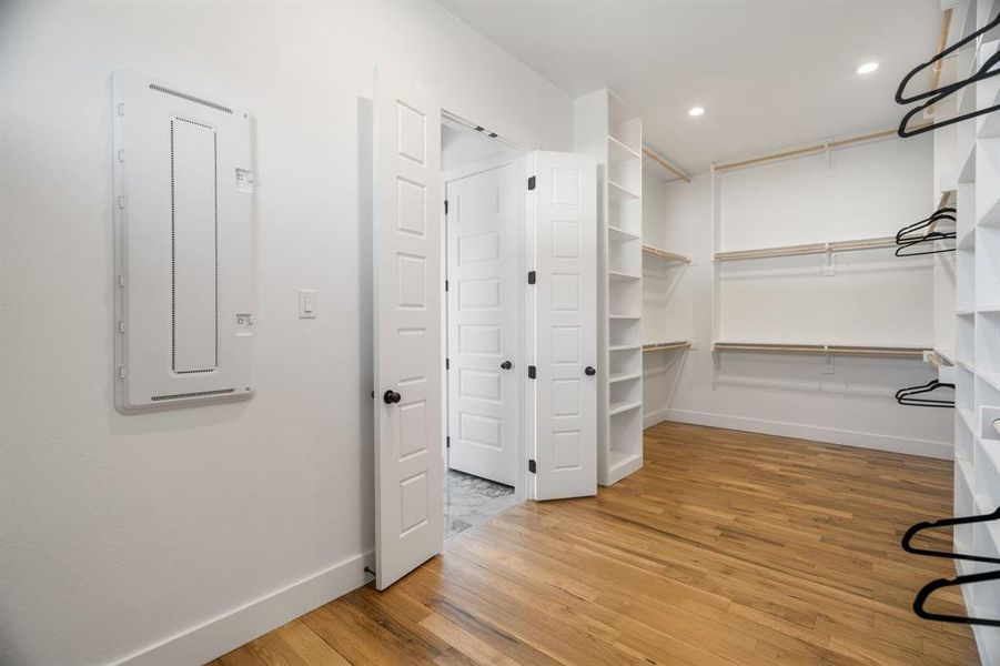 Walk in closet with electric panel and hardwood / wood-style floors