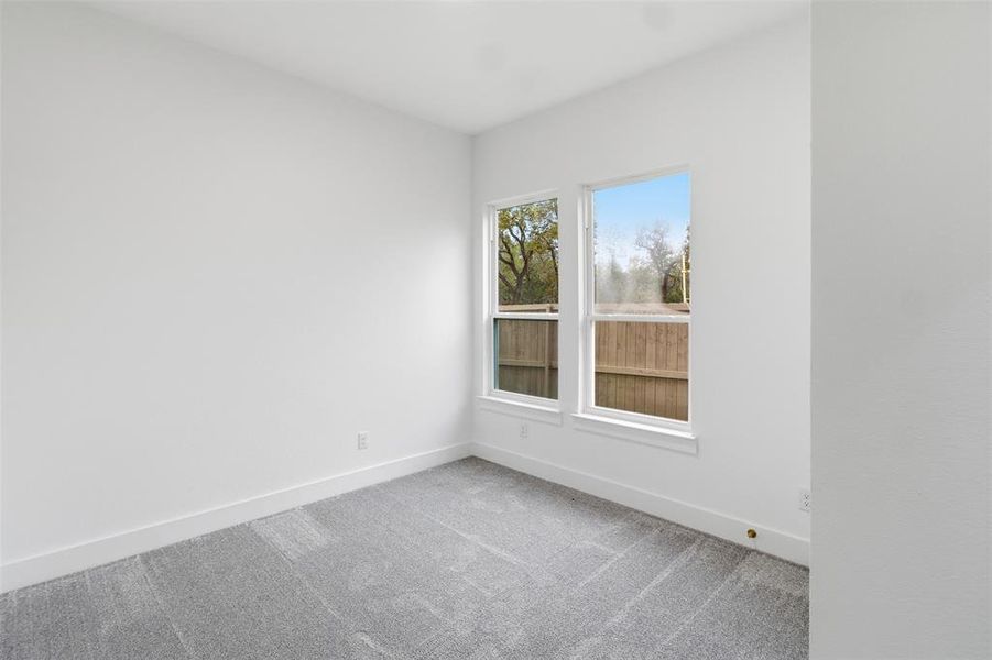 Carpeted spare room featuring baseboards