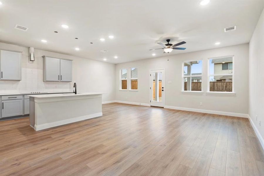 Unfurnished living room featuring ceiling fan, plenty of natural light, sink, and light hardwood / wood-style floors