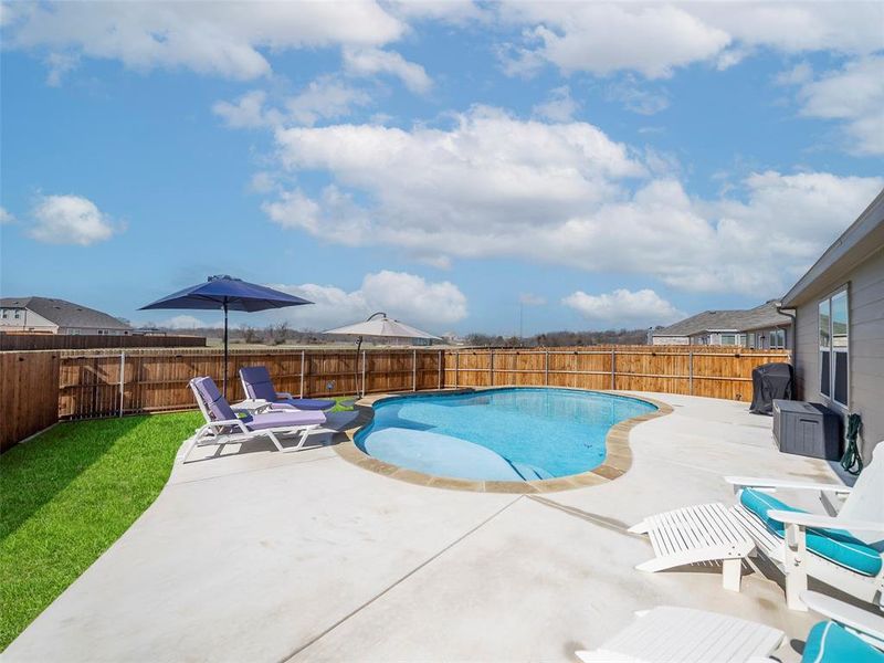 View of swimming pool with a patio area and a fenced backyard