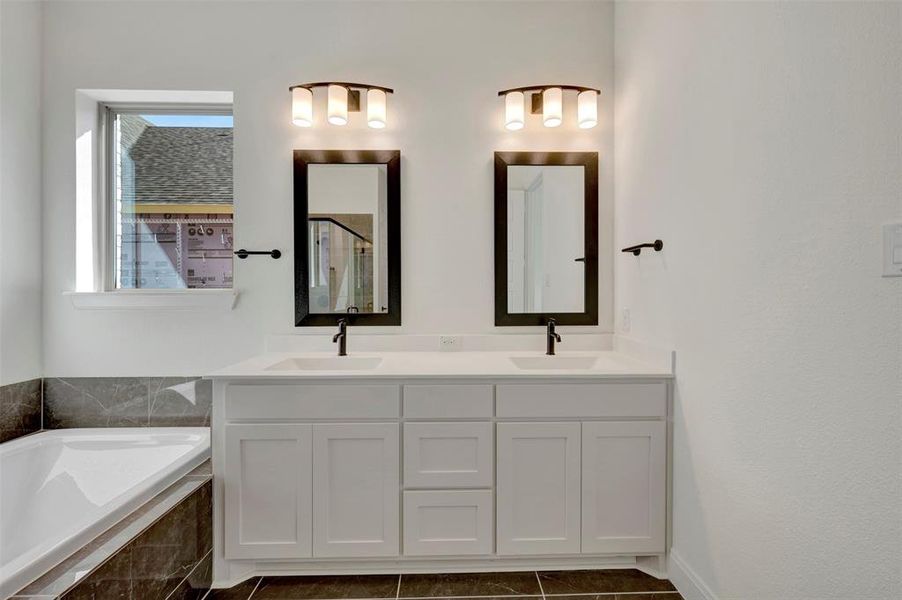 Full bathroom with double vanity, a bath, and dark tile patterned floors