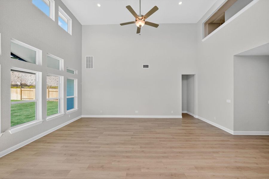 Unfurnished living room with light wood finished floors, ceiling fan, a towering ceiling, and recessed lighting Unfurnished living room with light wood finished floors, ceiling fan, a towering ceiling, and recessed lighting