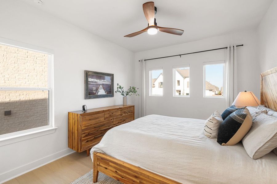 Bright interior space featuring light wood-finish flooring, a contemporary ceiling fan, and multiple windows Bright interior space featuring light wood-finish flooring, a contemporary ceiling fan, and multiple windows
