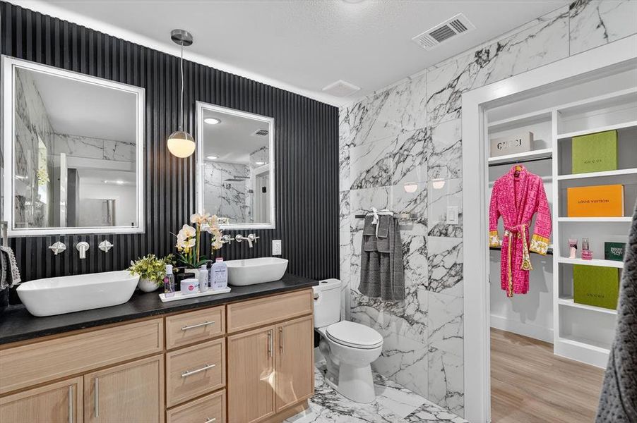 Dual vessel sinks with a black countertop and light wood-finish cabinetry