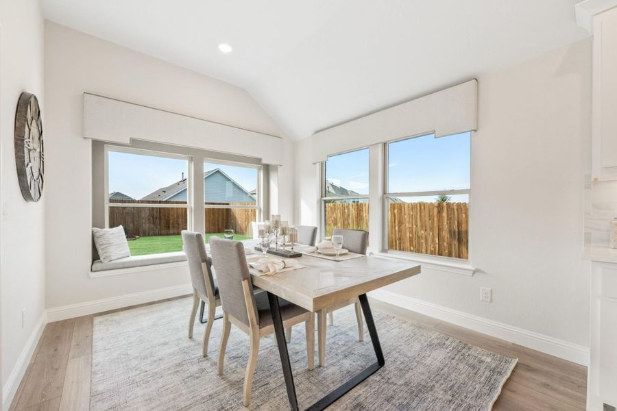 Dining area with wood table, gray chairs, vaulted ceiling, and large windows with backyard views Dining area with wood table, gray chairs, vaulted ceiling, and large windows with backyard views