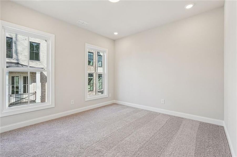 Plenty of natural light enters the secondary bedroom from large windows and recessed lighting