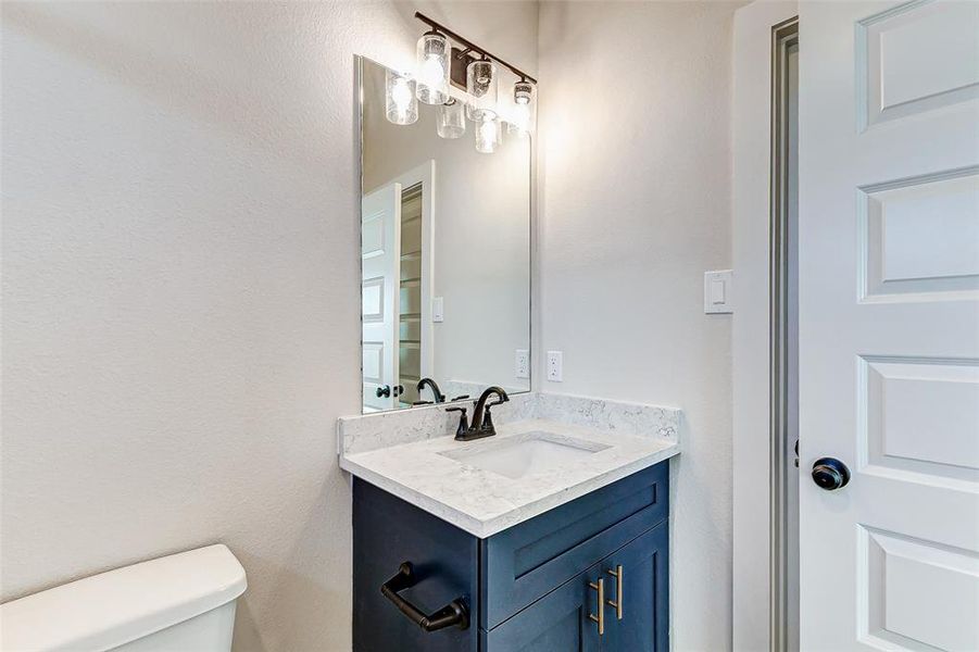 The guest bathroom boasts a stylish design with elegant marble-inspired tile, a classic tub-shower combo, and a chic vanity with quartz countertops. Matte black fixtures and modern lighting add a touch of sophistication.