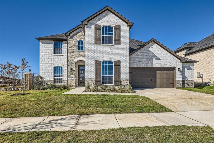 French country inspired facade with a garage and a front lawn