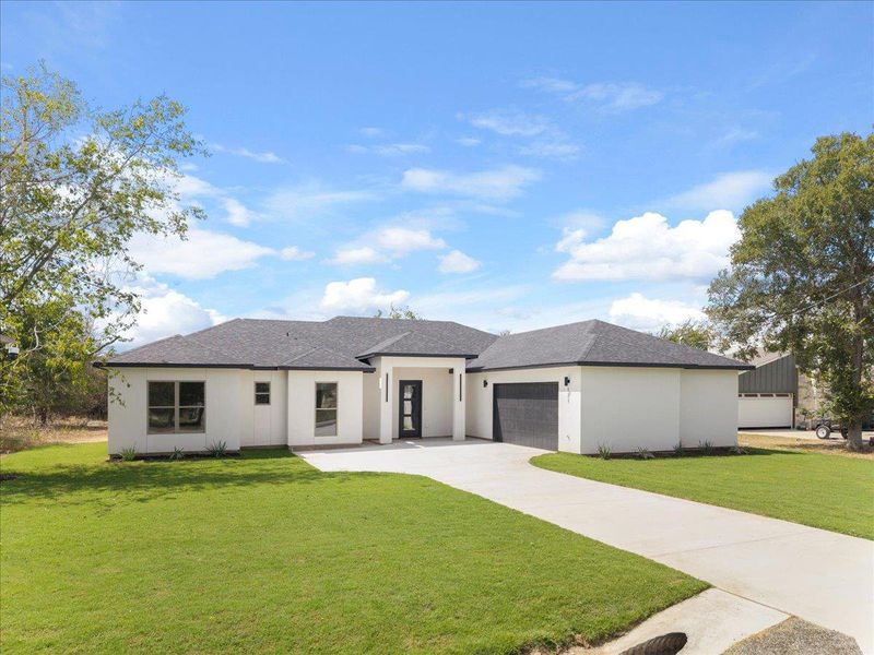 View of front of house with a front lawn, a shingled roof, driveway, and stucco siding View of front of house with a front lawn, a shingled roof, driveway, and stucco siding