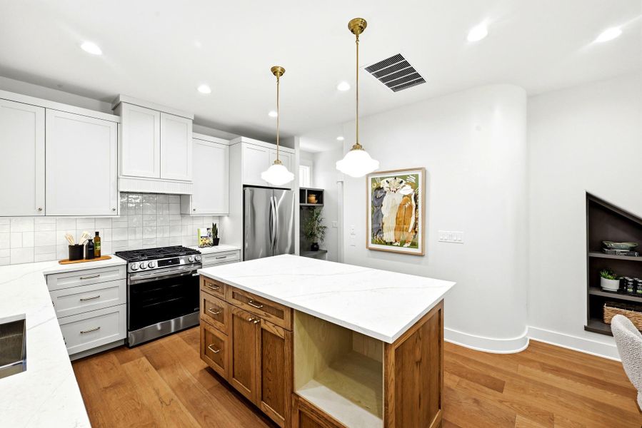 A well-appointed kitchen features stainless steel appliances, gleaming hardwood floors, and a practical island with stone counters. A well-appointed kitchen features stainless steel appliances, gleaming hardwood floors, and a practical island with stone counters.