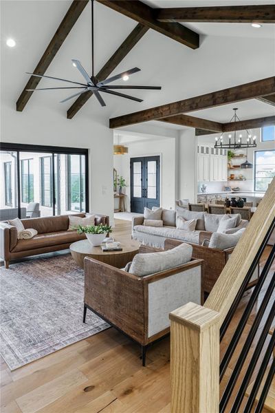 Living room featuring lofted ceiling with beams, a notable chandelier, light hardwood / wood-style floors, and french doors