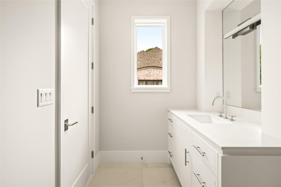 Private ensuite bath with a streamlined vanity, clean lines, and a window bringing in natural light.