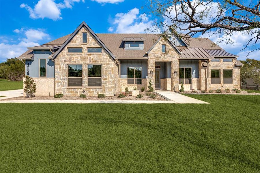 View of front of property featuring stone siding, a front lawn, a standing seam roof, a metal roof, and a shingled roof View of front of property featuring stone siding, a front lawn, a standing seam roof, a metal roof, and a shingled roof