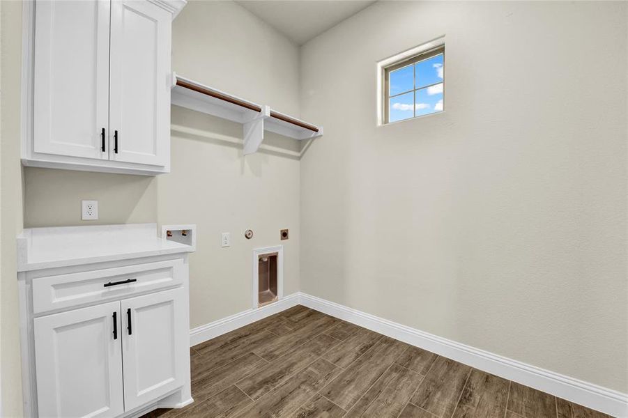 Laundry area with hookup for a washing machine, electric dryer hookup, cabinets, and dark hardwood / wood-style flooring