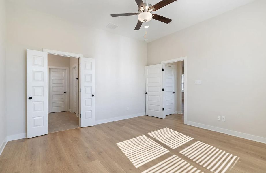 Spacious room featuring light wood-finish flooring and a contemporary ceiling fan with integrated lighting