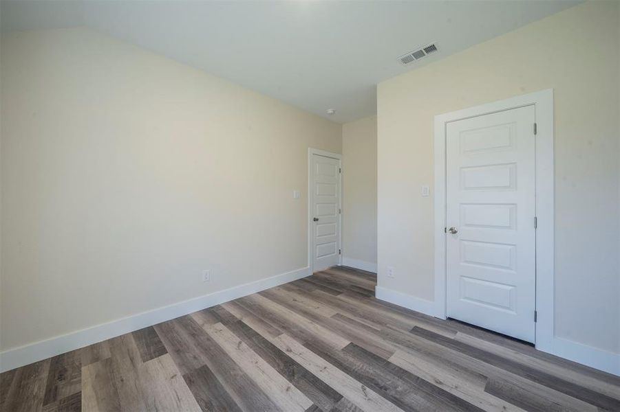 Unfurnished bedroom featuring baseboards, visible vents, and wood finished floors