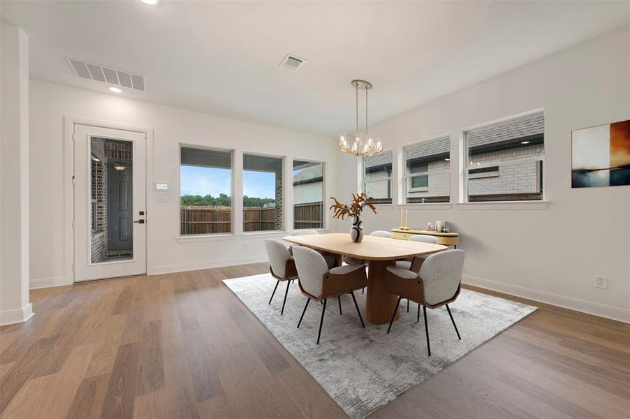 Dining area featuring light wood flooring, a decorative chandelier, and multiple windows providing natural light