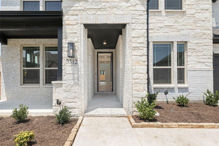 Home entrance with light stone exterior, covered entryway, black front door, and address number 3312 Home entrance with light stone exterior, covered entryway, black front door, and address number 3312
