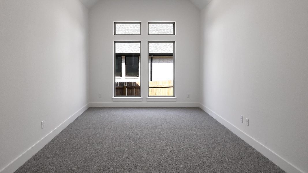 Spare room featuring lofted ceiling, carpet, and baseboards