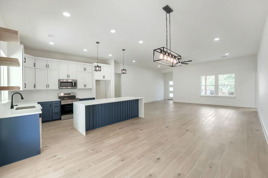 A well-appointed kitchen anchors an open-concept living space with sleek flooring and ample natural light.