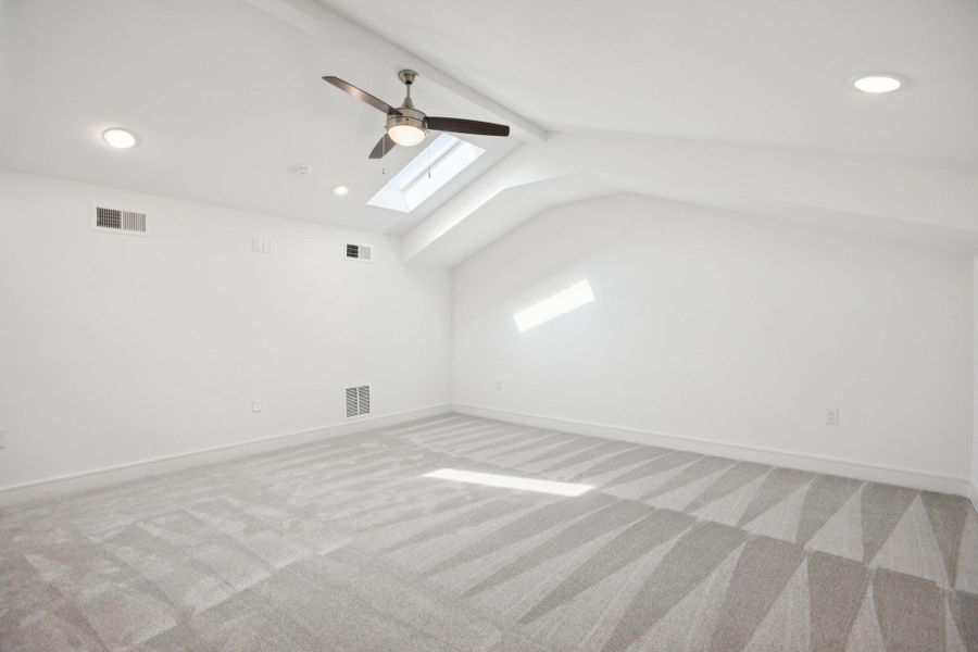 Additional living space featuring a ceiling fan, a skylight, light colored carpet, recessed lighting, and beam ceiling