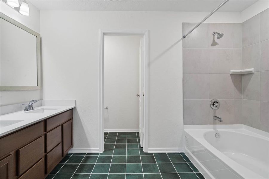 This primary bathroom is definitely move-in ready! Featuring dark stained cabinets with light countertops, high ceilings, custom paint, tile flooring, oversized tub and shower combination, sleek and dark modern finishes.