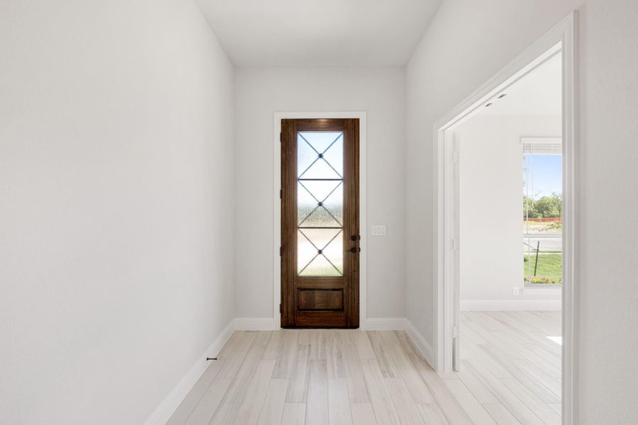 Entryway with dark wood front door featuring diamond glass panels and light hardwood floors