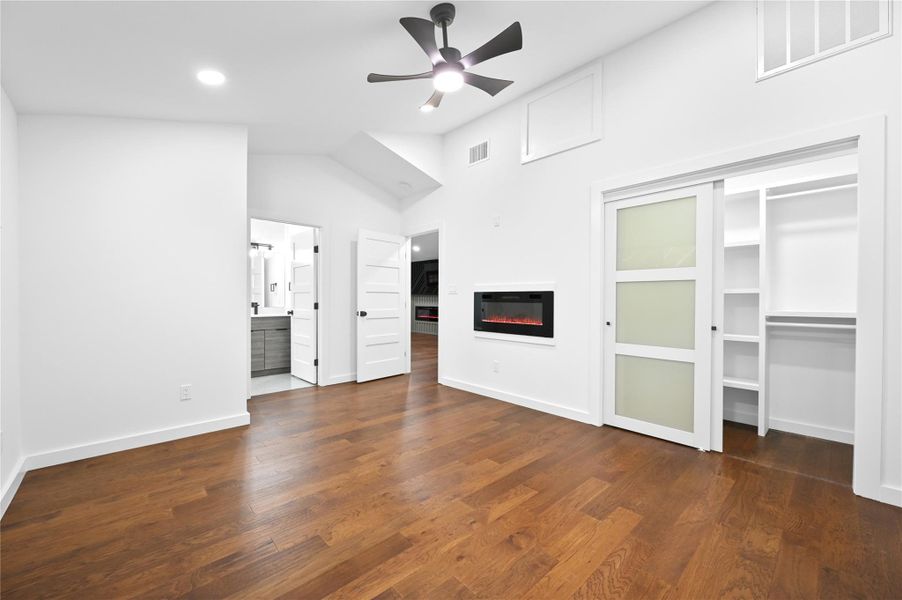 Unfurnished living room featuring a glass covered fireplace, a ceiling fan, wood finished floors, baseboards, and recessed lighting
