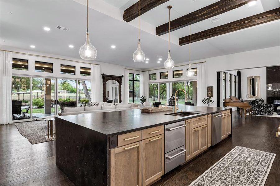 Kitchen with a center island with sink, decorative light fixtures, sink, and dark wood-type flooring