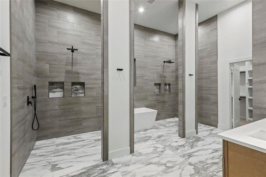 Bathroom with tile patterned flooring, tile walls, independent shower and bath, and vanity