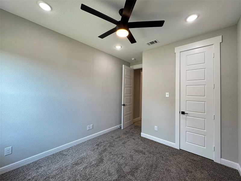 Bedroom featuring textured gray walls, recessed lighting, and a contemporary ceiling fan