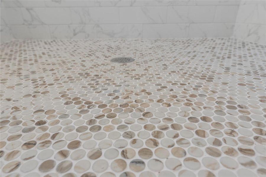 Exceeding décor expectations, this primary bathroom has refined character with custom and consistent tilework. Hints of latte and charcoal hues in the tiles coalesce to enhance the exquisite color scheme. Exceeding décor expectations, this primary bathroom has refined character with custom and consistent tilework. Hints of latte and charcoal hues in the tiles coalesce to enhance the exquisite color scheme.