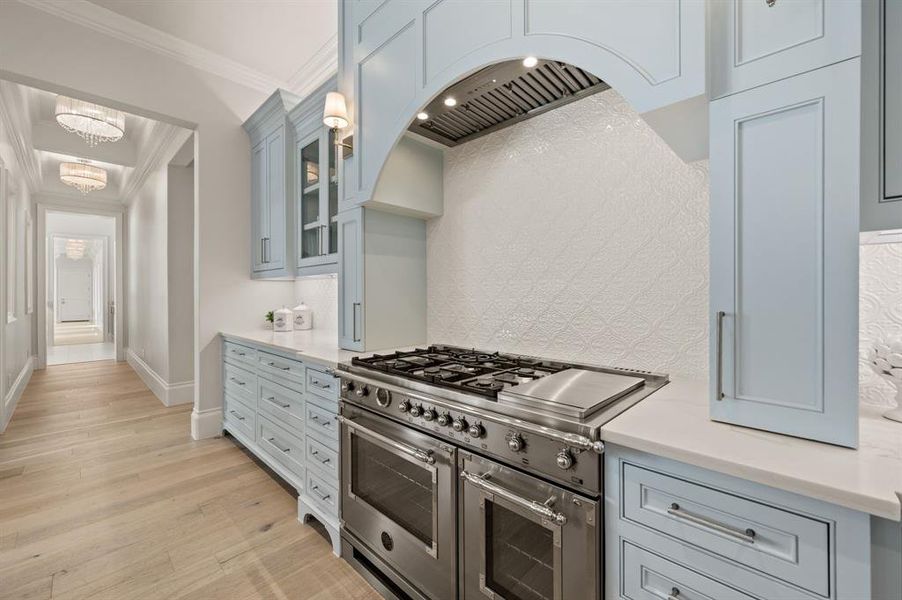 Kitchen featuring range with two ovens, light countertops, light wood finished floors, backsplash, and ornamental molding Kitchen featuring range with two ovens, light countertops, light wood finished floors, backsplash, and ornamental molding