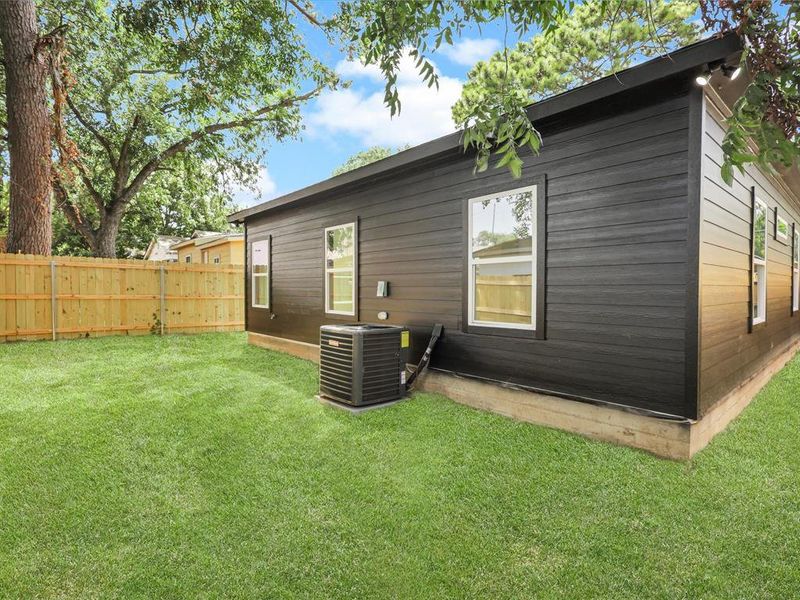 Rear view of property with central AC and a lawn