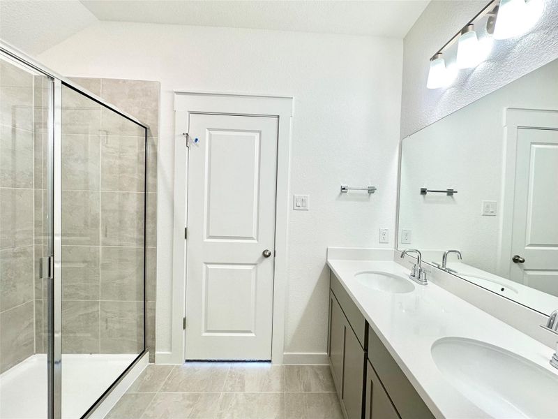 Bathroom with double vanity, a stall shower, and light tile patterned floors Bathroom with double vanity, a stall shower, and light tile patterned floors