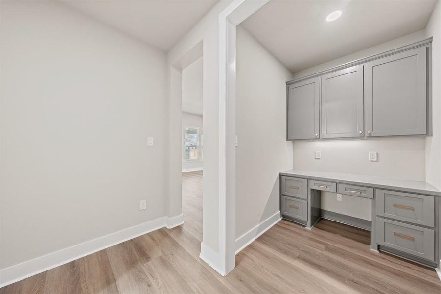 Unfurnished office featuring built in study area and light wood-style flooring